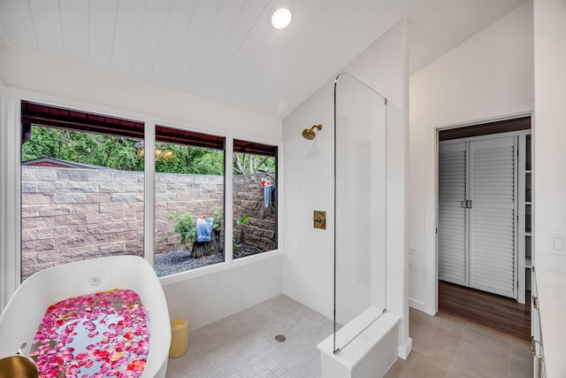 bathroom featuring a shower stall, a freestanding bath, vaulted ceiling, and tile patterned floors