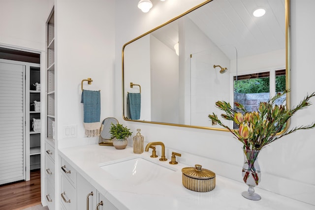 full bathroom featuring walk in shower, a walk in closet, vanity, wood finished floors, and lofted ceiling