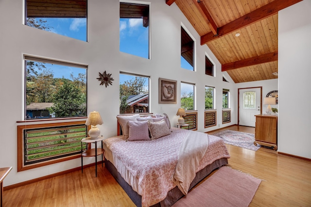 bedroom featuring high vaulted ceiling, light wood-style flooring, multiple windows, and beam ceiling