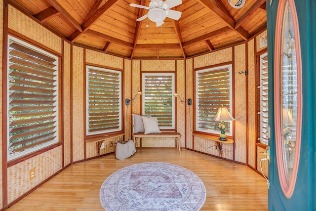 living area featuring lofted ceiling with beams, a ceiling fan, wood ceiling, wood finished floors, and wallpapered walls
