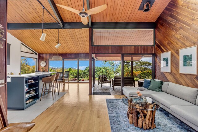 living room with wooden ceiling, ceiling fan, light wood-style floors, beam ceiling, and wood walls
