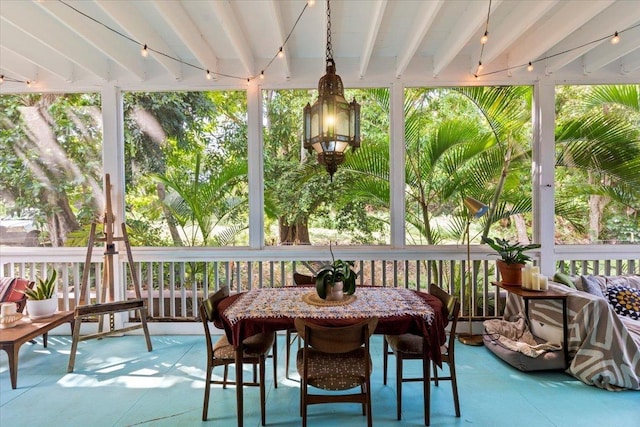 sunroom / solarium featuring a wealth of natural light, beamed ceiling, and rail lighting