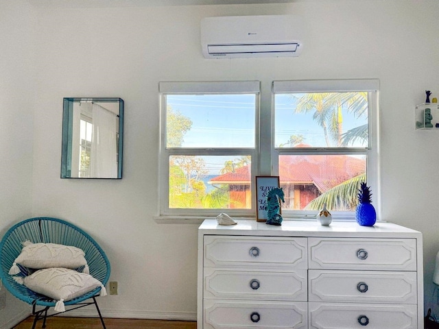 sitting room with hardwood / wood-style floors and a wall mounted AC