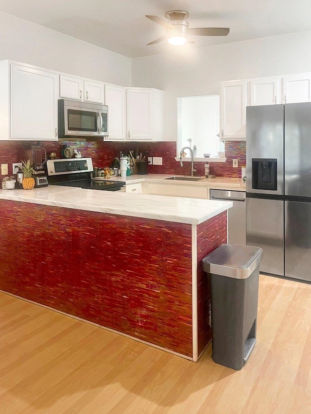 kitchen featuring sink, white cabinets, stainless steel appliances, and light wood-type flooring