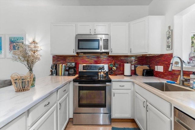 kitchen with backsplash, sink, white cabinets, and stainless steel appliances