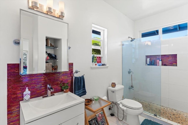 bathroom with a tile shower, tasteful backsplash, tile patterned flooring, toilet, and vanity