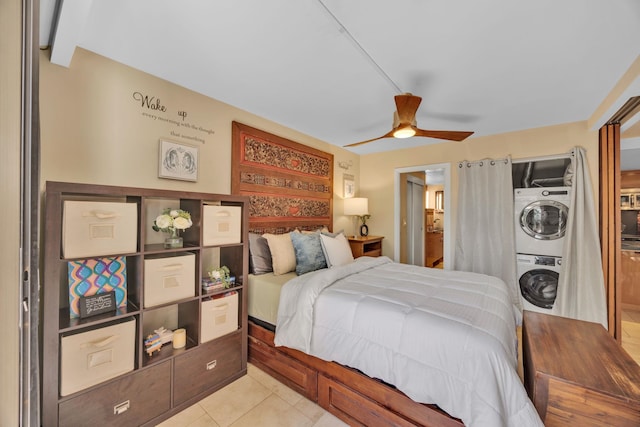 bedroom with ceiling fan, stacked washer and dryer, and light tile patterned floors