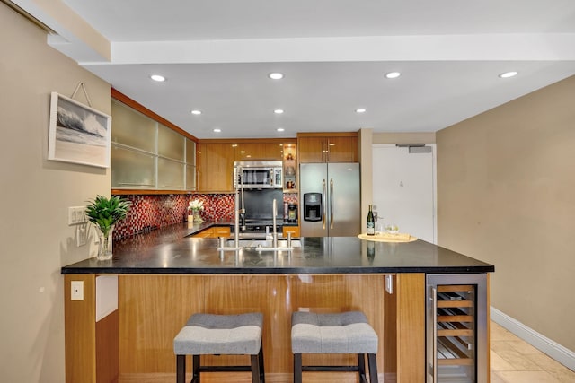 kitchen featuring sink, beverage cooler, a kitchen breakfast bar, kitchen peninsula, and stainless steel appliances