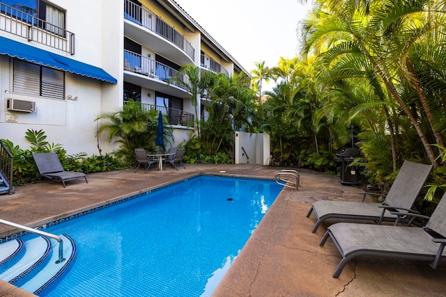 view of swimming pool with a patio, a wall mounted air conditioner, and grilling area