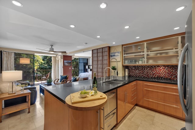 kitchen with sink, stainless steel refrigerator, ceiling fan, decorative backsplash, and kitchen peninsula