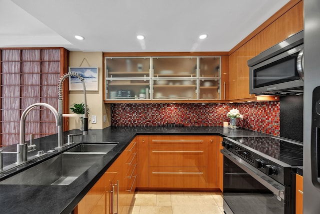 kitchen featuring tasteful backsplash, dark stone countertops, black electric range oven, and sink