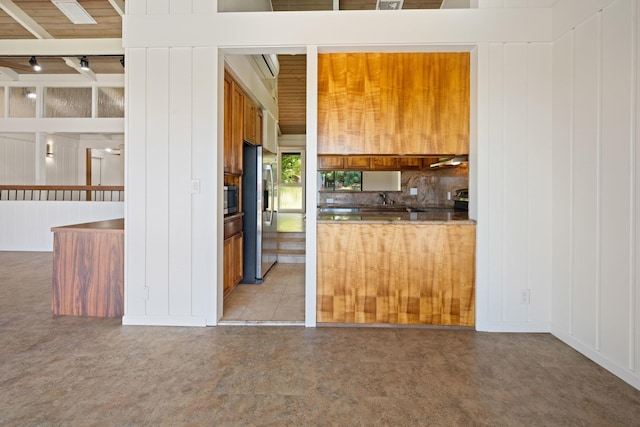 kitchen with dark countertops, backsplash, brown cabinets, a peninsula, and stainless steel appliances