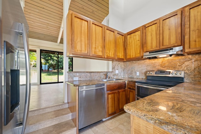 kitchen with a sink, stainless steel appliances, under cabinet range hood, tasteful backsplash, and brown cabinets