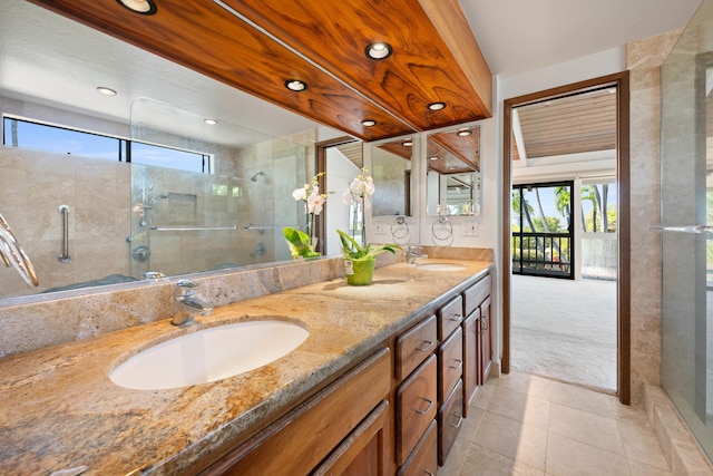 bathroom with double vanity, a shower with shower door, and a sink