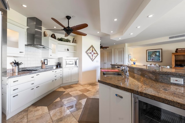 kitchen featuring decorative backsplash, wall chimney exhaust hood, white cabinetry, and wine cooler