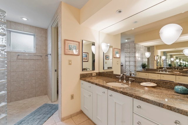 bathroom with a tile shower, tile patterned flooring, and vanity