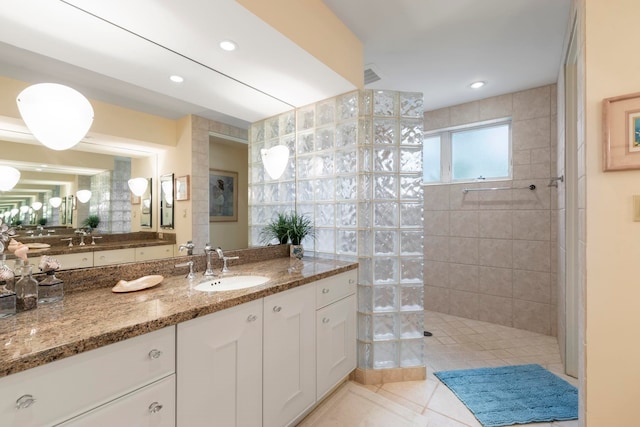 bathroom featuring vanity, a tile shower, and tile patterned floors