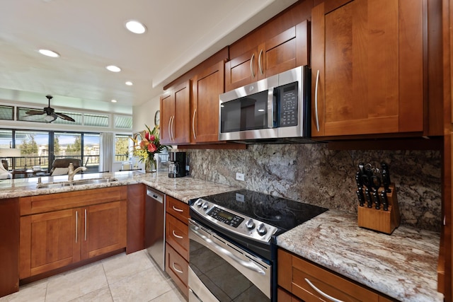 100 Ridge Rd Unit 723, Lahaina, HI 96761 - kitchen with appliances with stainless steel finishes, brown cabinets, a ceiling fan, decorative backsplash, and light stone countertops