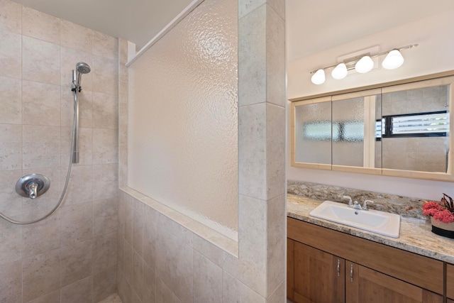 bathroom featuring tiled shower and vanity