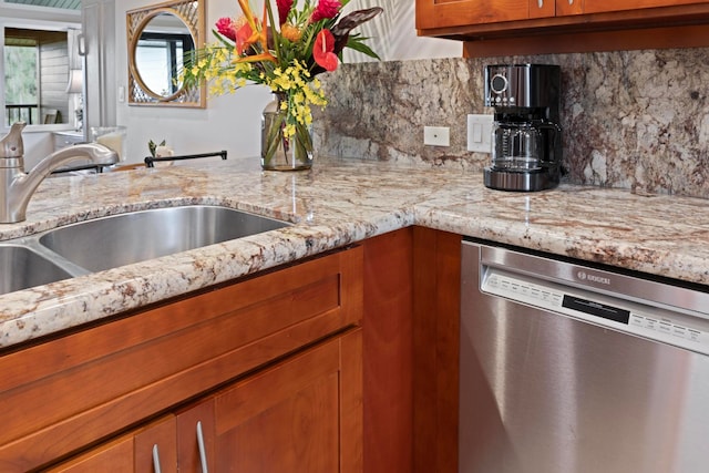 kitchen with decorative backsplash, light stone counters, sink, and stainless steel dishwasher