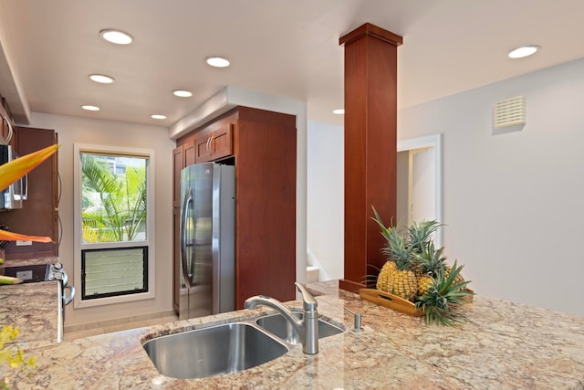 kitchen featuring light stone counters, stainless steel fridge, sink, and kitchen peninsula