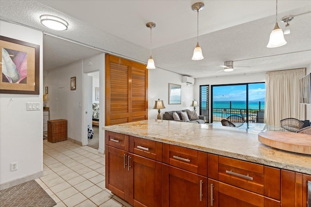 kitchen with decorative light fixtures, light stone counters, a textured ceiling, and light tile patterned flooring