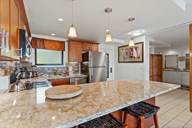 kitchen with decorative light fixtures, decorative backsplash, light stone counters, a breakfast bar area, and stainless steel appliances