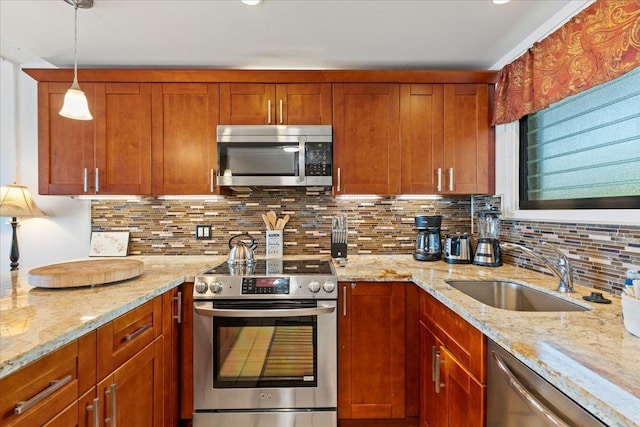 kitchen featuring sink, decorative light fixtures, light stone countertops, and appliances with stainless steel finishes