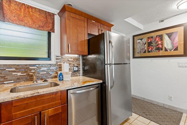 kitchen with appliances with stainless steel finishes, decorative backsplash, sink, light stone counters, and light tile patterned floors