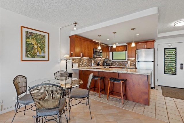 kitchen featuring hanging light fixtures, appliances with stainless steel finishes, tasteful backsplash, light tile patterned floors, and a textured ceiling