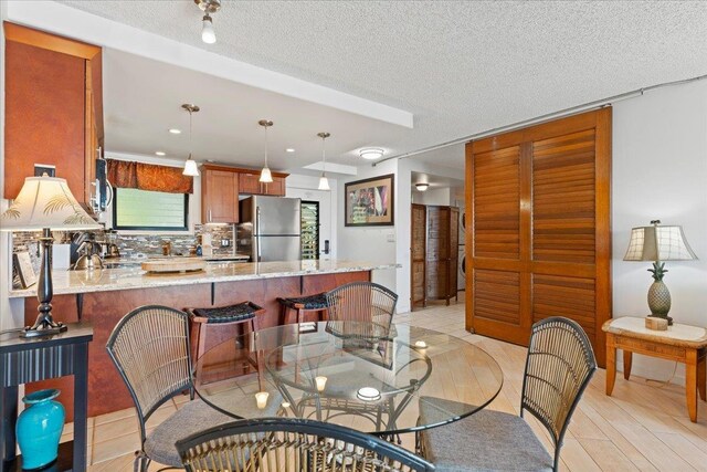 dining area featuring a textured ceiling, a wealth of natural light, and light wood-type flooring