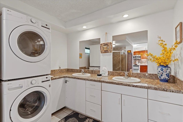 washroom featuring stacked washer / dryer, light tile patterned flooring, sink, and a textured ceiling