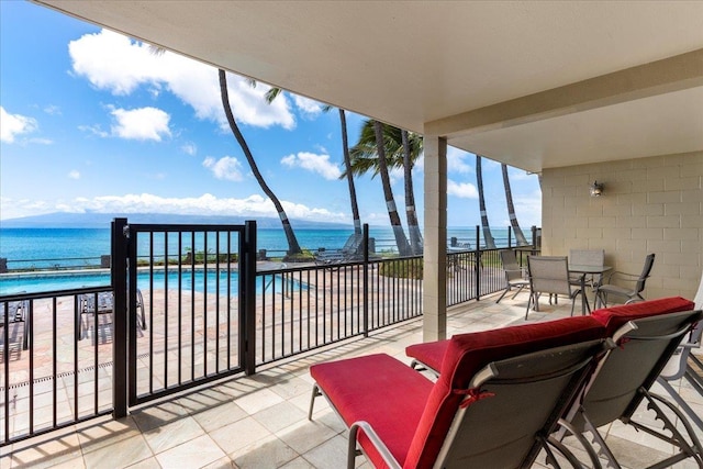 view of patio with a water view, a community pool, and a beach view