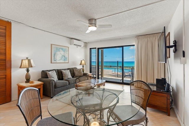 living room with a textured ceiling, a water view, a wall unit AC, and ceiling fan