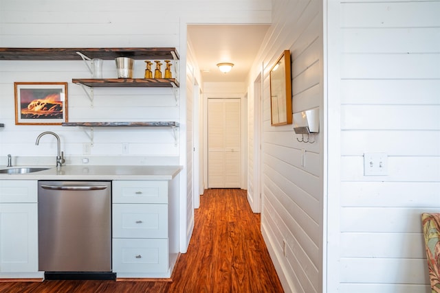 kitchen with white cabinetry, dishwasher, sink, dark hardwood / wood-style floors, and wood walls