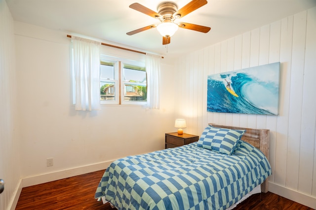 bedroom featuring ceiling fan, dark hardwood / wood-style floors, and wooden walls