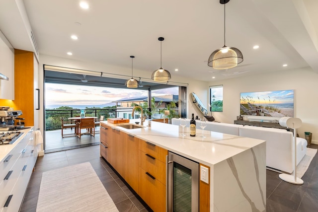 kitchen with wine cooler, plenty of natural light, a large island with sink, and sink