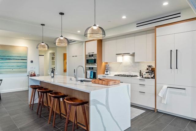 kitchen featuring a center island with sink, white cabinets, and pendant lighting