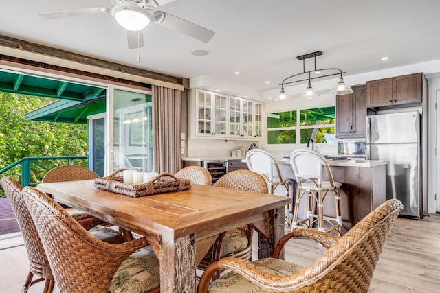 dining space with ceiling fan, light wood-type flooring, and beverage cooler