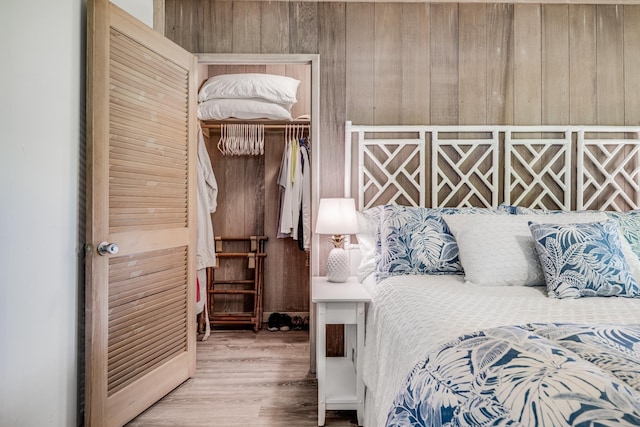 bedroom with a closet, wood walls, and hardwood / wood-style floors