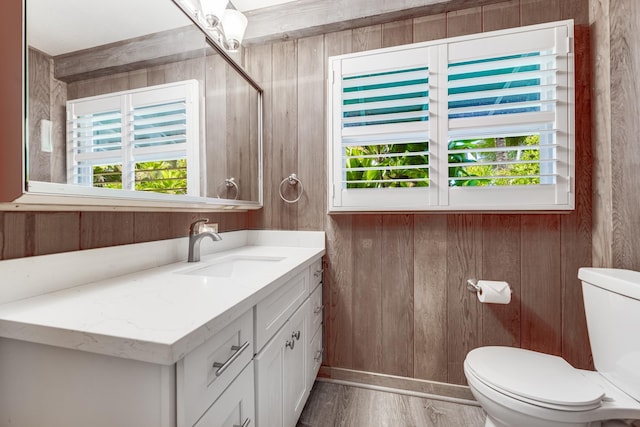 bathroom featuring wooden walls, vanity, hardwood / wood-style flooring, and toilet