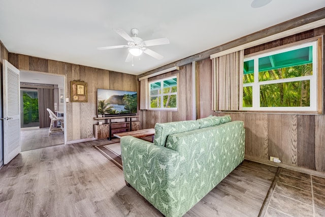 unfurnished living room featuring ceiling fan and wooden walls