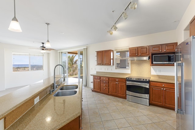 kitchen featuring sink, stainless steel appliances, light stone counters, decorative backsplash, and decorative light fixtures