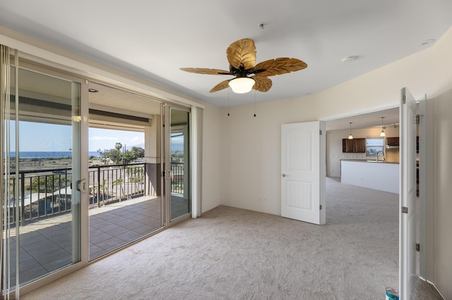 unfurnished room featuring ceiling fan, a mountain view, sink, and light carpet