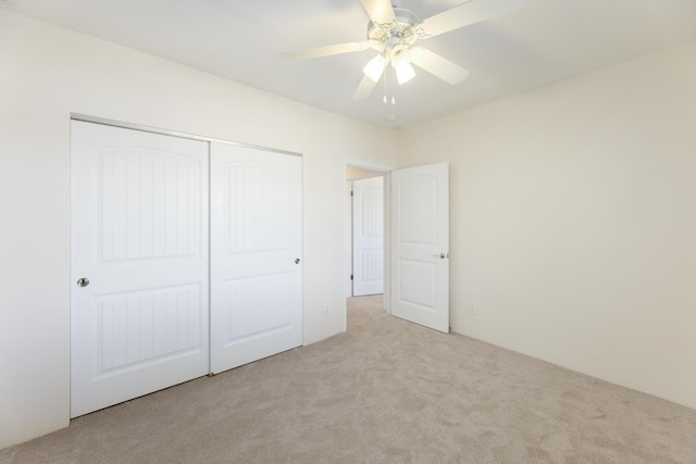 unfurnished bedroom featuring light colored carpet, a closet, and ceiling fan