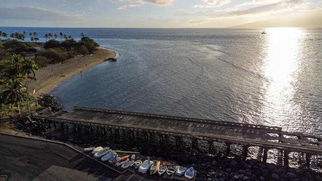 aerial view at dusk featuring a water view and a view of the beach