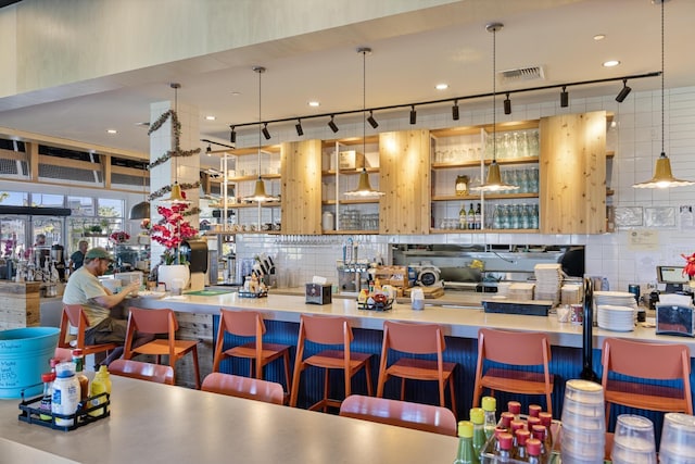 kitchen with hanging light fixtures, decorative backsplash, and a kitchen breakfast bar