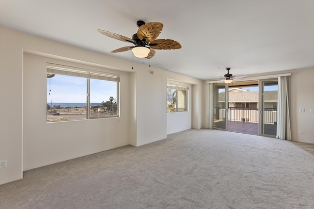 unfurnished room with ceiling fan, light colored carpet, and a wealth of natural light