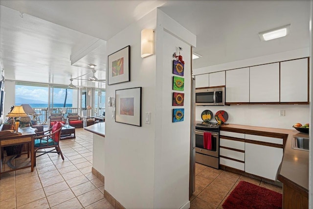70 Hauoli St Unit 217, Wailuku, HI 96793 - kitchen featuring appliances with stainless steel finishes, white cabinetry, open floor plan, a wall of windows, and light countertops