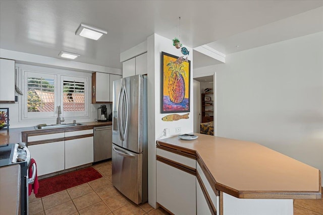 70 Hauoli St Unit 217, Wailuku, HI 96793 - kitchen with stainless steel appliances, a sink, a peninsula, light tile patterned floors, and white cabinetry